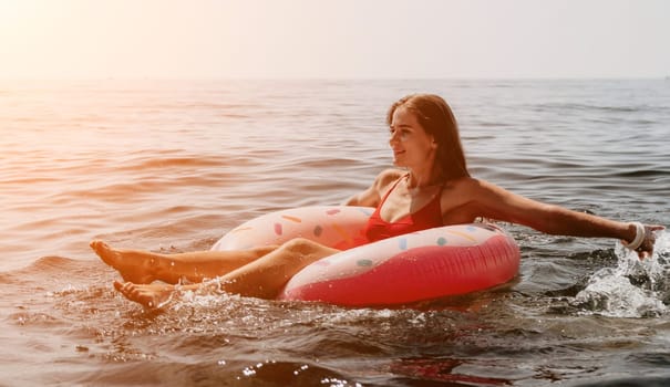 Woman summer sea. Happy woman swimming with inflatable donut on the beach in summer sunny day, surrounded by volcanic mountains. Summer vacation concept