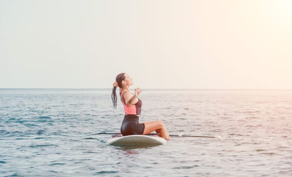 Silhouette of woman standing, surfing on SUP board, confident paddling through water surface. Idyllic sunset or sunrise. Sports active lifestyle at sea or river.