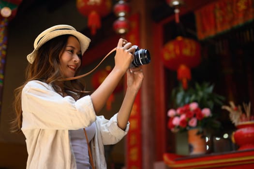Attractive female tourist taking photo with her camera at Chinatown district in Chiang Mai, Thailand.