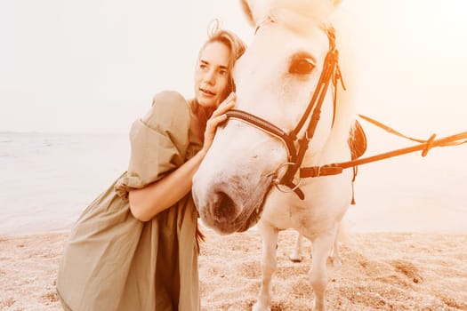 A woman in a dress stands next to a white horse on a beach, with the blue sky and sea in the background