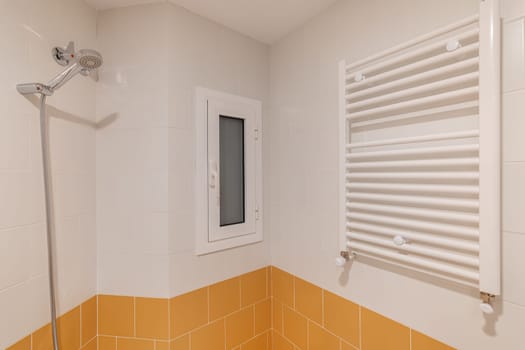 A corner view of a modern shower area featuring a handheld showerhead and two-tone tiles