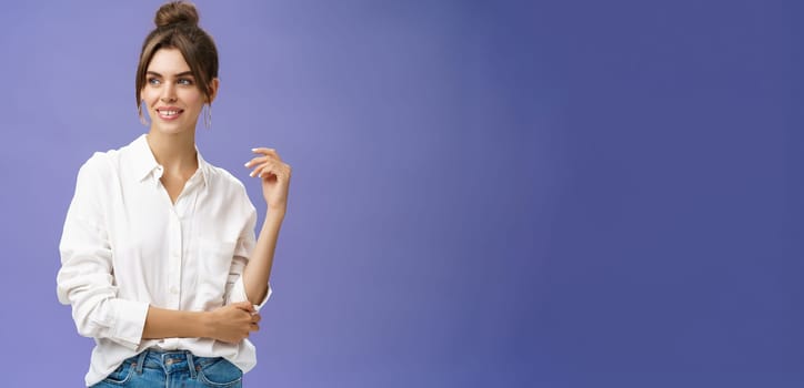 Feminine and stylish modern charming girl with gapped teeth and pimple posing in trendy white blouse and round earrings gazing left charmed and sensual with cute smile over purple background. Lifestyle.