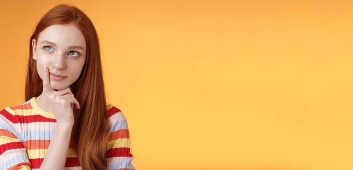 Creative thoughtful young smart redhead female student thinking ideas project look upper left corner dreamy touching lip pondering choice, taking important decision what order, orange background.