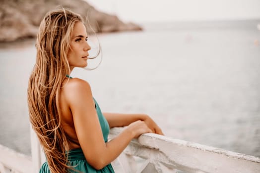 Woman sea green dress. Side view a happy woman with long hair in a long mint dress posing on a beach with calm sea bokeh lights on sunny day. Girl on the nature on blue sky background