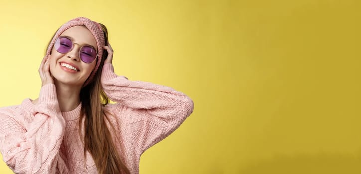 Waist-up shot of lovely glamour carefree young woman ready for vacation, packing bags move out of winter, travelling, smiling joyfully close eyes happily, touching face, wearing sunglasses sweater.