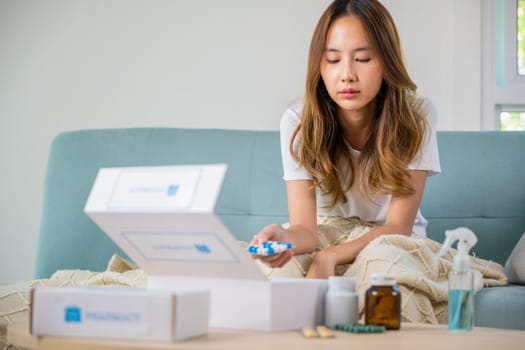 Sick people reading information medicine label pills, female with flu virus, Asian young woman reading ingredient and hold bottle drug on sofa in living room at home, Healthcare and medicine concept