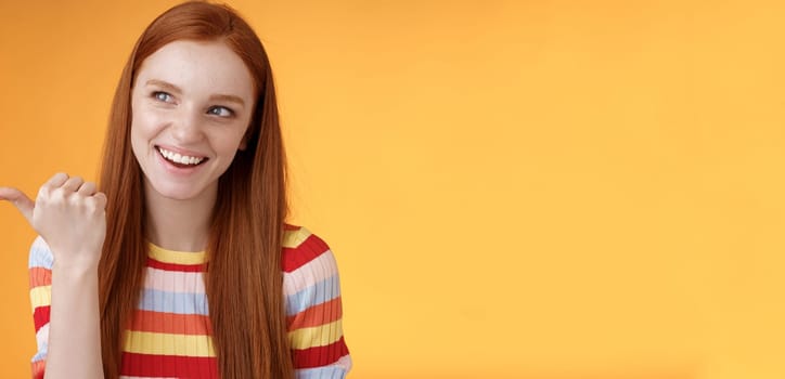 Amused outgoing redhead stylish female student discuss girly things smiling cheeky pointing handsome guy smirking devious pointing thumb looking intrigued curiously staring orange background.