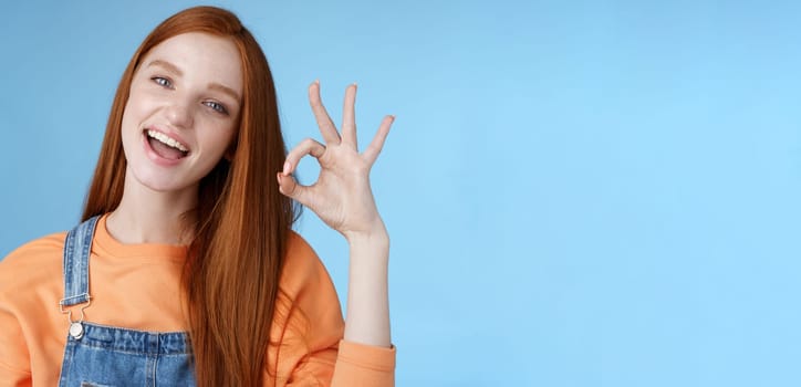 Studio shot carefree happy attractive european redhead girl show okay ok sign smiling white teeth approval confirmation recommend good product agree terms give positive feedback, think idea perfect.