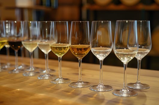 Linear arrangement of glasses with different shades of white wine displayed on a wooden table in a tasting room