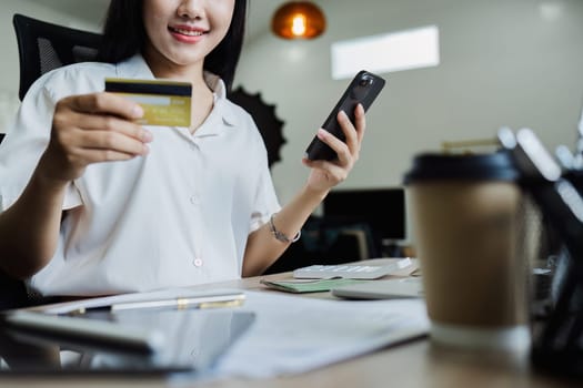 Young woman makes a financial transaction on the Internet on the laptop with mobile.