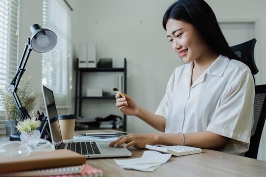 Young woman makes a financial transaction on the Internet on the laptop with mobile.