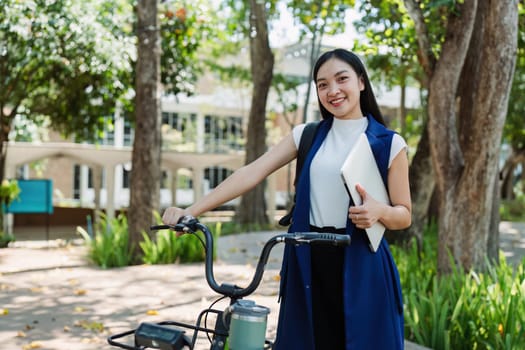 Young businesswoman sitting on stair in city park and using laptop for work hybrid. Bike to work eco friendly alternative vehicle green energy.