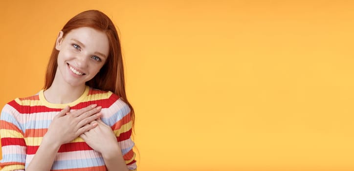 Pleased tender feminine good-looking redhead woman receive compliment confession touch heart feel warmth dearest moment smiling delighted lovely keep love inside soul, standing orange background.