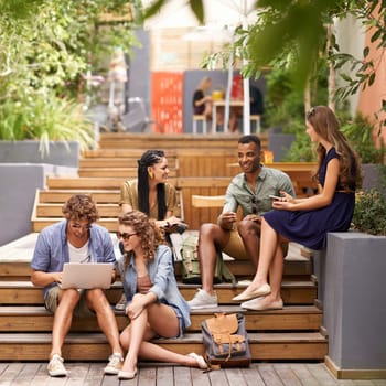 Friends, happy and laptop or cellphone on break, campus and browse on social media for update. Students, diversity and technology at university for online research and talking to relax or networking.