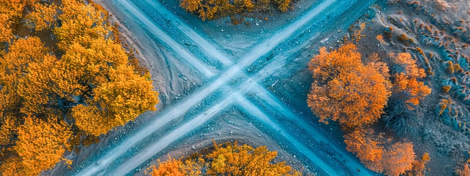 Overhead shot of a dirt crossroads surrounded by trees with fall foliage