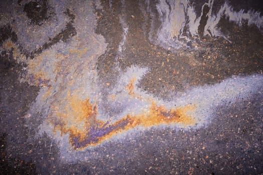 Textured stain of fuel or oil on wet asphalt on a rainy day. The concept of environmental pollution.