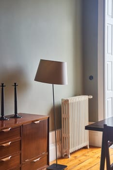 A lamp sits on a wooden floor next to a dresser in a house. The furniture is beautifully crafted with wood cabinetry and wood stain, enhancing the interior design of the room