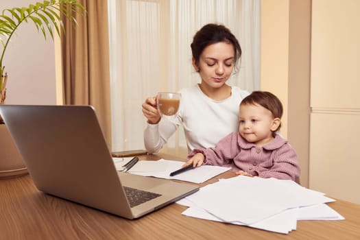Cheerful pretty businesswoman working at home with her little child girl