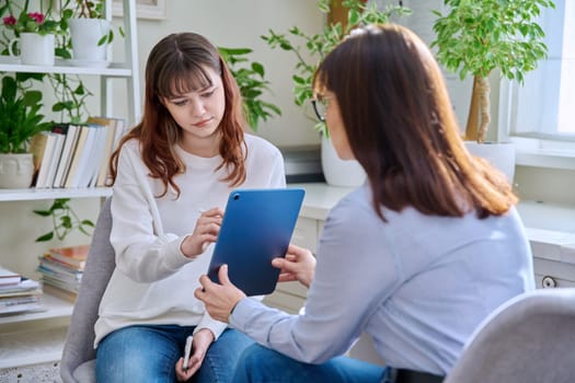 Teenage girl college student at therapy meeting with mental health professional social worker psychologist counselor sitting together in office. Psychology, psychotherapy, mental assistance support