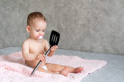 the child develops with interest while playing with a kitchen spatula.