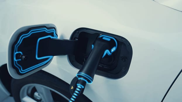 Closeup EV charger plugged into electric car for electric recharging from electric charging station with glowing light cable. Cutting-Edge innovation and future green energy sustainability. Peruse