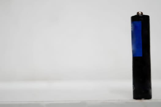 Single AAA-Size Battery Standing Upright on a White Surface