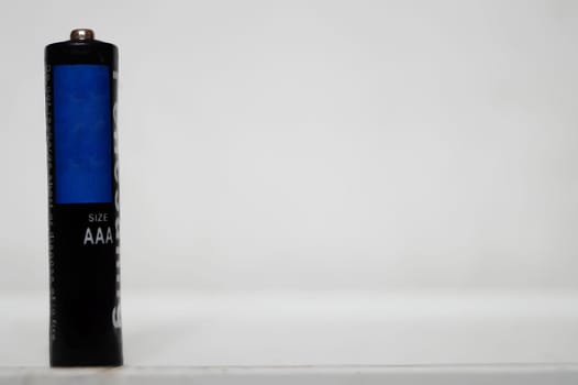 Single AAA-Size Battery Standing Upright on a White Surface