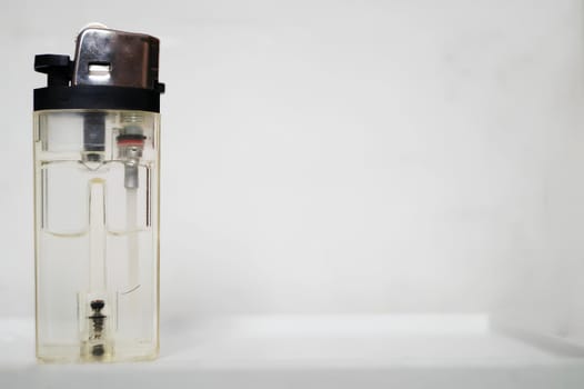 Transparent Plastic Lighter With Brown Cap Against a White Background