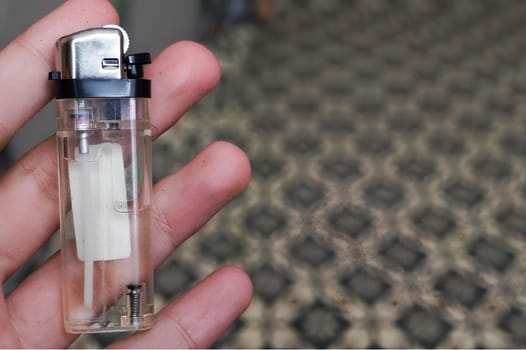 Close-Up View of a Hand Holding a Transparent Gas Lighter Indoors