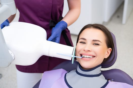 A dental assistant facilitates the patients preparation for an X ray with the aid of specialized instruments.