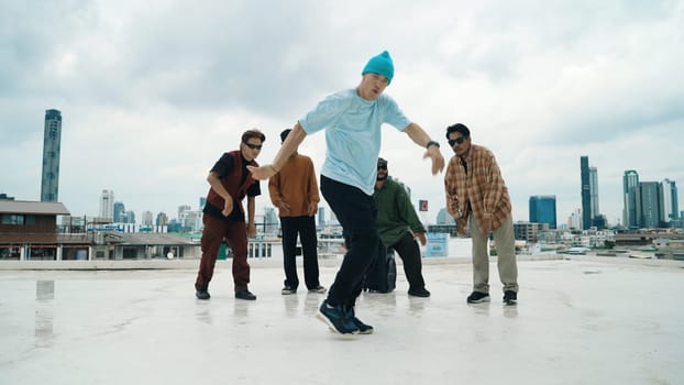 Professional break dance team practice B-boy dance while multicultural friends at rooftop. Young modern dancing group doing hip hop movement. Style,fashion,action. Outdoor sport 2024. Endeavor.