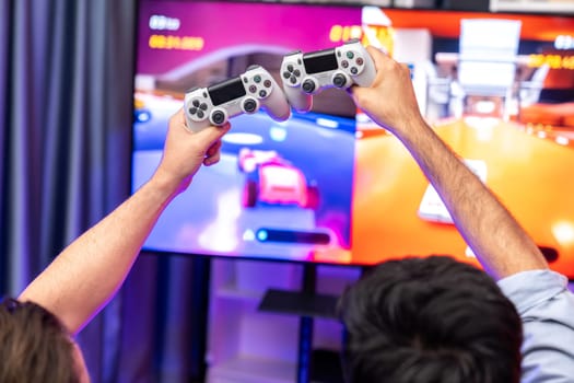 Close up photo of holding joystick crashing or cheerful friends on car racing competition of video game on blurred screen. Concept of lifestyles gamer on weekend with friend in living room. Sellable.