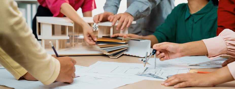 Professional architect team select sustainable house materials while skilled engineer using divider measure blueprint with house model and color palette placed on meeting table. Closeup. Variegated.