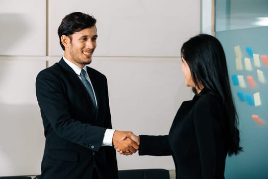 Business people agreement concept. Businessman and Asian businesswoman do handshake in the office. uds