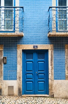 A blue door with the number 13 painted on it stands out on the brick facade of the building. The rectangle fixture is made of azure wood, a unique choice of building material