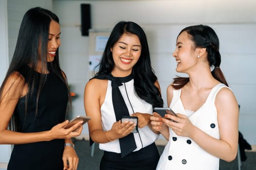 Three women friends having conversation while looking at mobile phone in their hands. Concept of social media, gossip news and online shopping. uds