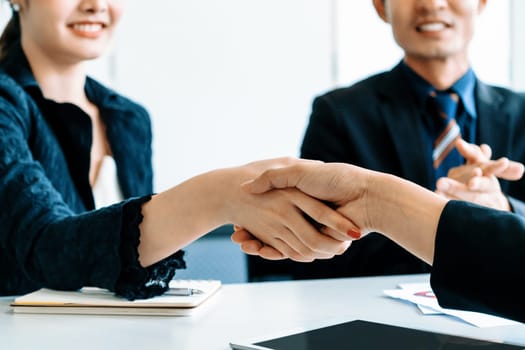 Business people agreement concept. Businessman and Asian businesswoman do handshake in the office. uds