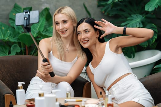 Two beautiful content creator making natural beauty and cosmetic tutorial on green plant garden video. Beauty blogger showing how to beauty care to social medial audience using selfie stick . Blithe