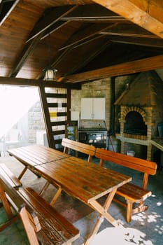 Tables and benches stand in a wooden gazebo near the stove in the courtyard of the house. High quality photo