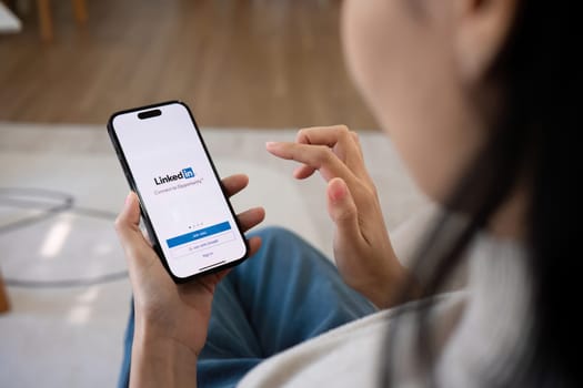 CHIANG MAI, THAILAND, FEB 27,2024 : A women holds Apple iPhone 14 Pro Max with LinkedIn application on the screen.LinkedIn is a photo-sharing app for smartphones..