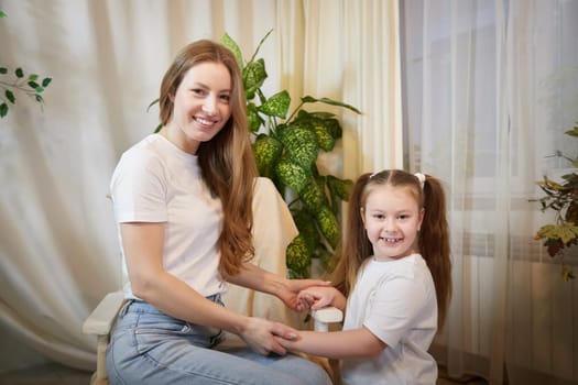 Happy loving family. Mother and her teenager daughter child girl playing and hugging in living room with flower