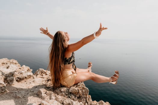 Woman travel sea. Happy tourist taking picture outdoors for memories. Woman traveler looks at the edge of the cliff on the sea bay of mountains, sharing travel adventure journey.