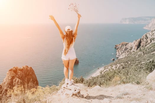 Woman travel sea. Young Happy woman in a long red dress posing on a beach near the sea on background of volcanic rocks, like in Iceland, sharing travel adventure journey