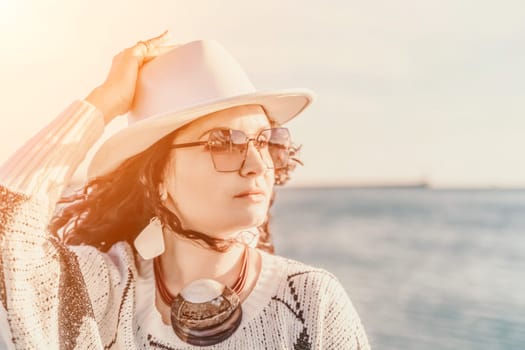 Portrait of a curly haired woman in a white hat and glasses on the background of the sea