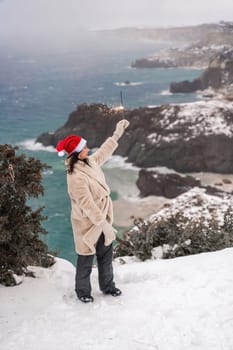 Outdoor winter portrait of happy smiling woman, light faux fur coat holding heart sparkler, posing against sea and snow background.