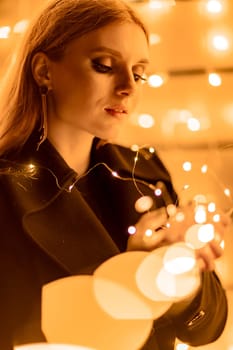 Christmas mood. Woman with long hair in sity decorated for Christmas. She is dressed in a black coat