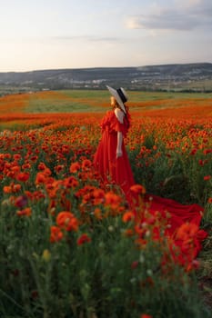 Woman poppy field red dress hat. Happy woman in a long red dress in a beautiful large poppy field. Blond stands with her back posing on a large field of red poppies