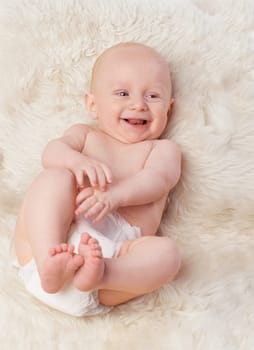 Baby, cute and laugh in bedroom, blanket and playtime in diaper for child development in happiness. Infant, kid and wellness for newborn, adorable and rug in house for home and toddler fun.