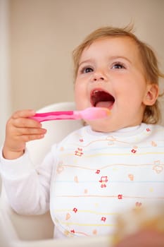 Baby girl, spoon and eating for nutrition, food and development with happiness at home, house and living room. Female child, infant and kid excited for feeding, breakfast and snack for growth.