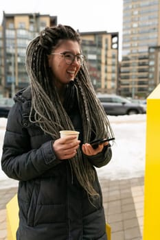 Photo on the street, young pretty informal woman with dreadlocks hairstyle smiling sweetly.